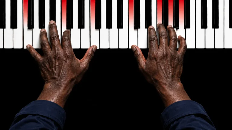 Dłonie bluesmana grającego na pianinie z czerwonym podświetleniem klawiszy
